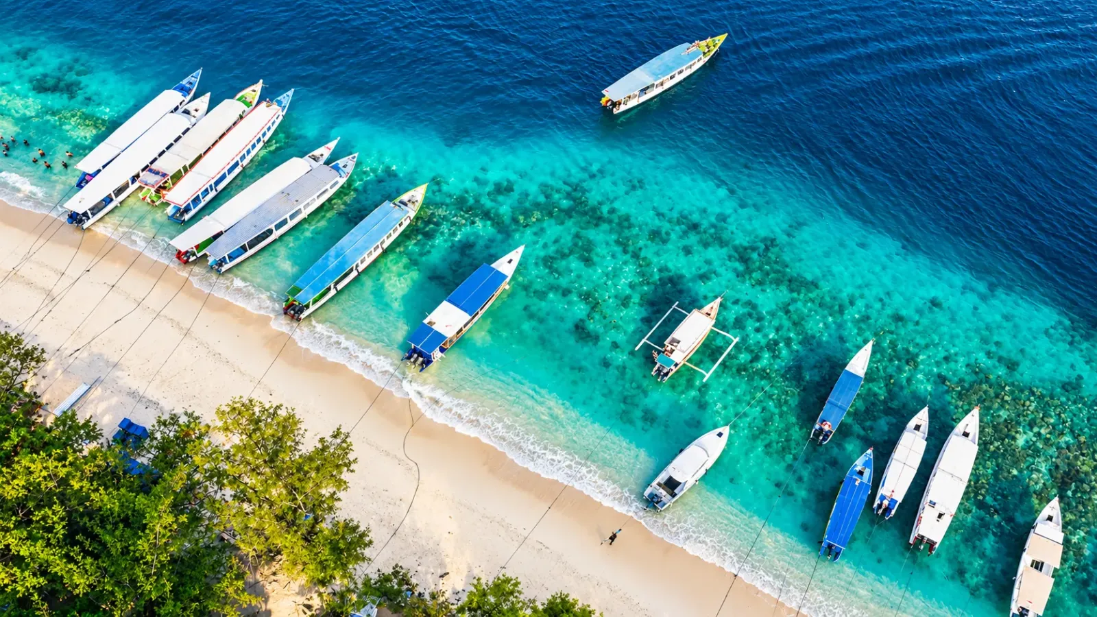 Bãi biển cát trắng nước xanh và thuyền nhỏ tại quần đảo Gili Indonesia