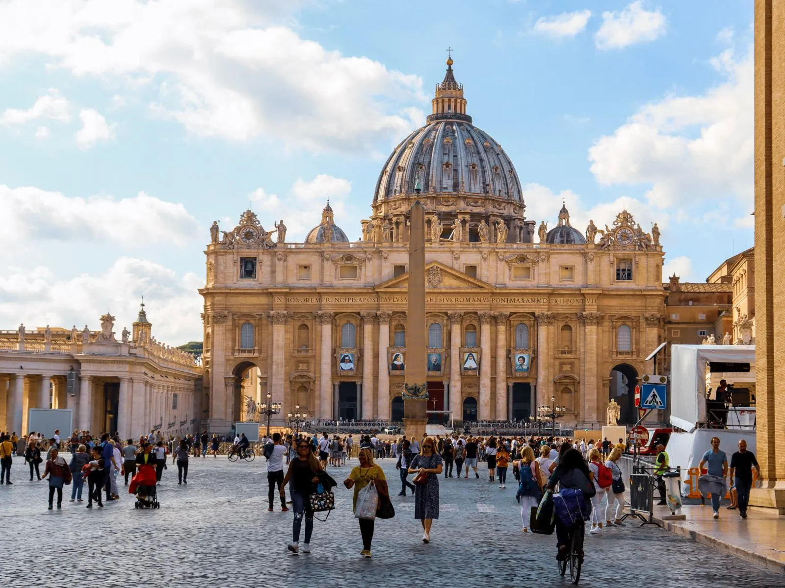 Mặt tiền Vương cung thánh đường Thánh Phêrô nhìn từ quảng trường Vatican với hàng cột hai bên, các bức tượng và du khách tham quan phía trước