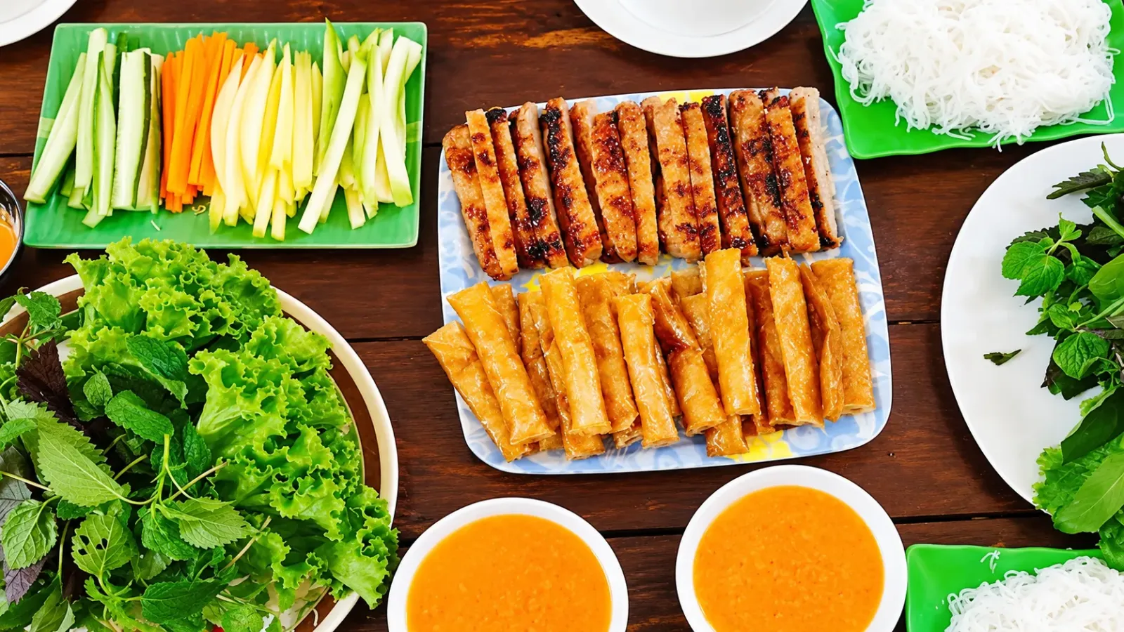 Phần nem nướng Nha Trang ăn kèm rau xanh, bánh tráng và chén nước chấm