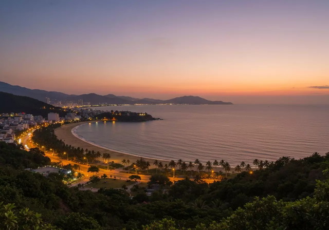 Toàn cảnh thành phố Nha Trang lúc hoàng hôn với màu sắc ấm áp, tầm nhìn panorama bao quát vẻ đẹp thiên nhiên của đường bờ biển và ánh đèn thành phố trong khung cảnh yên tĩnh đầy chất thơ