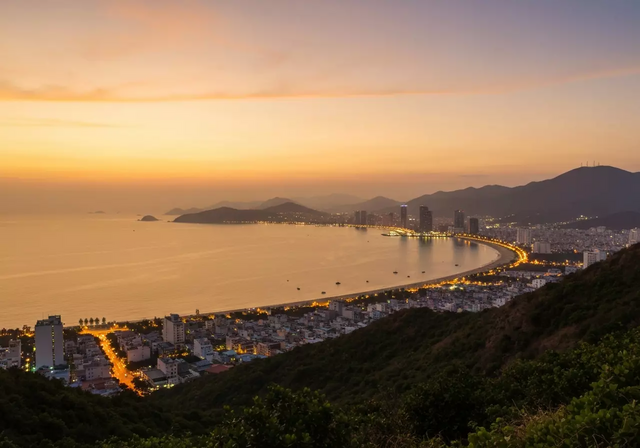 Toàn cảnh thành phố Nha Trang lúc hoàng hôn với màu sắc ấm áp, tầm nhìn panorama bao quát vẻ đẹp thiên nhiên và ánh đèn thành phố trong khung cảnh yên tĩnh đầy chất thơ.